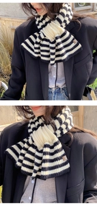Detail view of black and white striped knitted scarf with a brown leather logo label