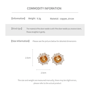 Détail de boucles d'oreilles soleil plaquées or avec zircon ambre et aiguille en argent