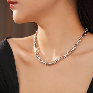 Close-up of a silver geometric interlocking chain link necklace on model neckline