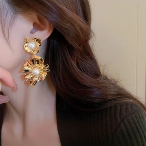 Gros plan de boucles d'oreilles fleurs dorées avec perles sur mannequin