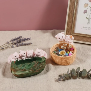 Close-up of creative pink pig resin succulent pots with cabbage and basket designs