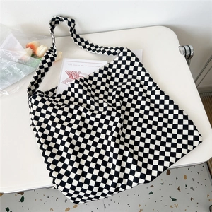 Flat lay of checkerboard canvas tote bag with floral accents on a white desk