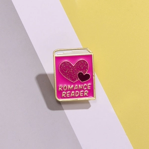 Detail of pink Romance Reader enamel pin with glitter heart and gold metal borders