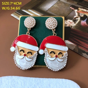 Detail of Christmas Santa earrings with red enamel and pearl stud on green velvet base