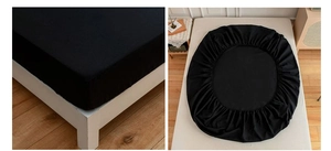 Detail of black fitted sheet with elastic band edge showing mattress corner fit