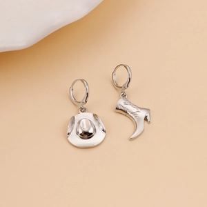 Polished silver alloy cowboy boot and hat mismatched hoop earrings on beige background