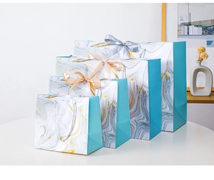 Four sizes of marble pattern gift bags with gold accents and silk ribbon bows