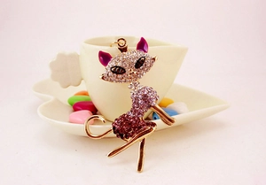 Macro detail of cat keychain pendant with pink and purple rhinestones on gold metal