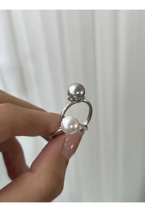 Dettaglio di anelli in argento s925 con perle bianche e grigie indossati sulla mano