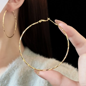 Close-up of golden hammered hoop earrings showing delicate texture and metallic luster