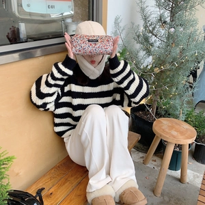 Floral corduroy stationery pouch held by a model in a cozy, vintage lifestyle setting