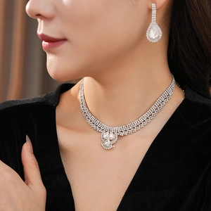 Detailed view of silver necklace and teardrop earrings with crystals on a model