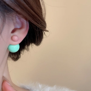 Detail of pink and mint green double ball resin stud earrings on a female model