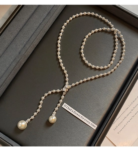 Detailed view of elegant Y-shaped pearl necklace with zircon accents on velvet tray