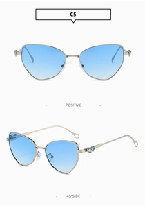 Detail view of silver cat-eye sunglasses with blue heart rhinestones and gradient lenses