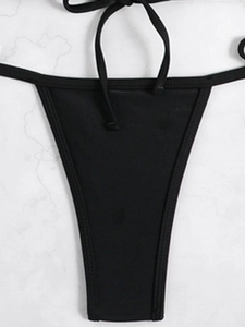 Detail of black tie-side bikini bottoms with fine stitching on white marble surface