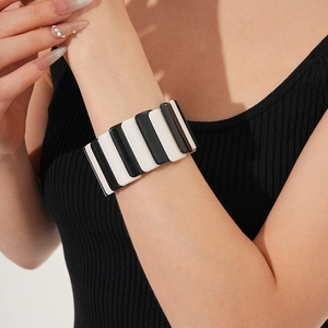 Detail view of a wide black and white striped elastic resin bracelet worn on a wrist