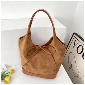 Detail view of large brown suede tote bag with leather strap and decorative bow accent