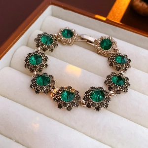 Detailed macro shot of vintage flower bracelet with green gems in white velvet jewelry box