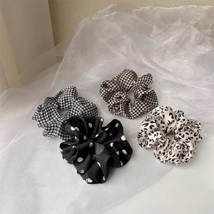 Detail of four silk satin hair scrunchies in polka dot, houndstooth and leopard patterns