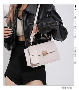 Detail of white quilted handbag with a large gold heart lock and matching small coin purse