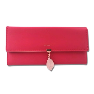 Detail of rose pink long wallet with gold brand lettering and leaf-shaped leather pendant