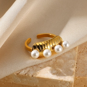 Detail of gold pearl ring featuring four white pearls on a textured metal band