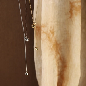 Detail of adjustable Y-shaped necklace with gold and silver beads on fine snake chains