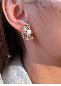 Detailed close-up of a twisted gold hollow earrings with pearls and pavé cubic zirconia