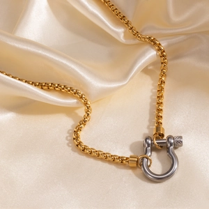 Detail of 18k gold box chain with silver horseshoe shackle pendant on satin silk
