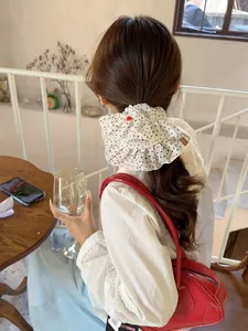 Detail of white polka dot scrunchie with layered ruffles and heart label on a ponytail
