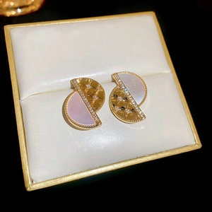 Detail showing gold geometric earrings with diamond inlay and mother of pearl finish