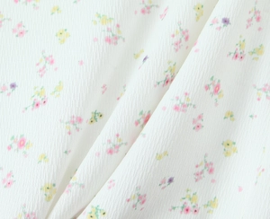 Détail du tissu en maille côtelée blanche avec un imprimé floral rose et jaune