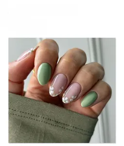 Détail d'ongles ronds courts vert avocat avec des motifs floraux de marguerites blanches