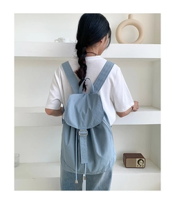 Zaino in nylon azzurro indossato da una modella in un ambiente minimalista moderno