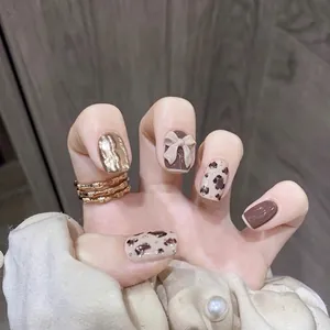 Handmade leopard print and bow press-on nails in brown and gold tones with metallic accents