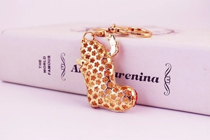 Close-up of golden hollow Christmas boot pendant keychain on a classic book background