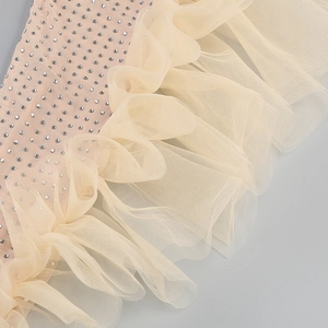 Detail of ruffle mesh with sparkling rhinestone embellishments on a beige party dress