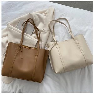 Flat lay of brown and beige soft leather tote bags with a blazer and book