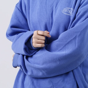 Macro detail of the white logo embroidery on a blue crewneck sweatshirt with fine fabric texture