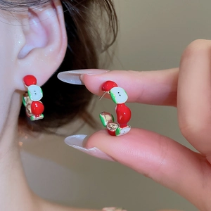 Detail of red and green apple stud earrings with drip oil finish on metal