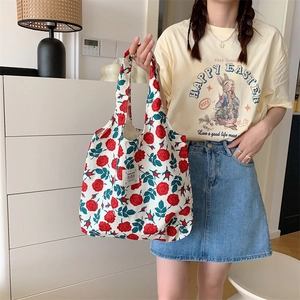 Borsa tote in tela a fiori con rose rosse portata da modella in ambiente lifestyle