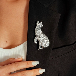 Close-up of a silver cat brooch with artistic patterns on a black suit lapel