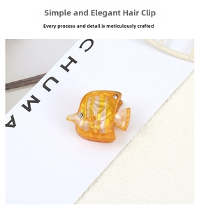 Macro detail of tropical fish hair clip with yellow acetate texture and rhinestone eyes