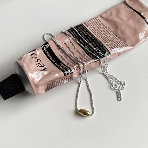 Minimalist S925 sterling silver bead chain necklace with gold oval pendant on pink prop