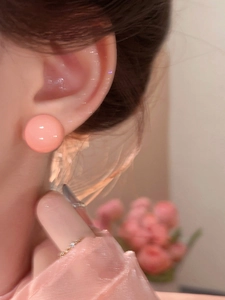 Close-up shot of a sweet pink round stud earring worn on an ear, showing minimalist style