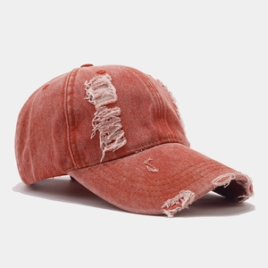 Détail de la casquette de baseball en denim rouge brique usée avec bords effilochés