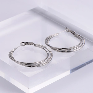 Elegant silver triple-hoop earrings with textured metal layers on acrylic stand