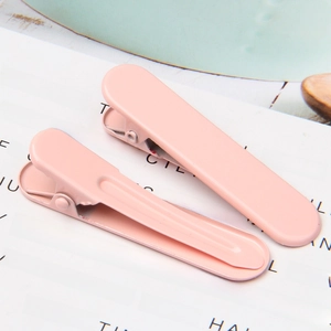 Close-up of matte pink metal duckbill hair clips with a smooth finish and minimalist design