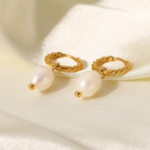 Detailed close-up of 18K gold twisted hoop earrings with elegant pearl pendants on silk